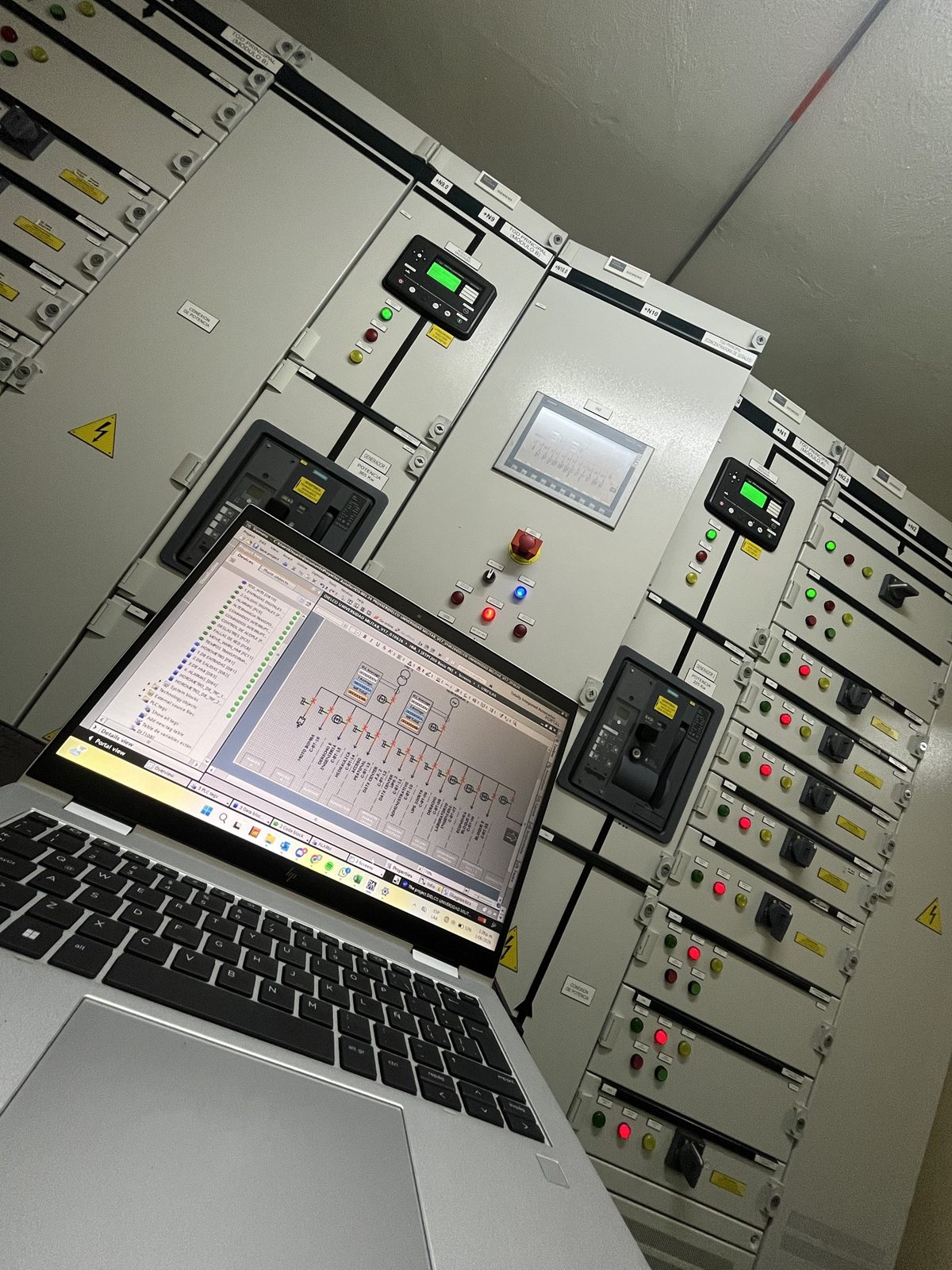 Computador portátil con el programa del PLC frente a un tablero de distribución
